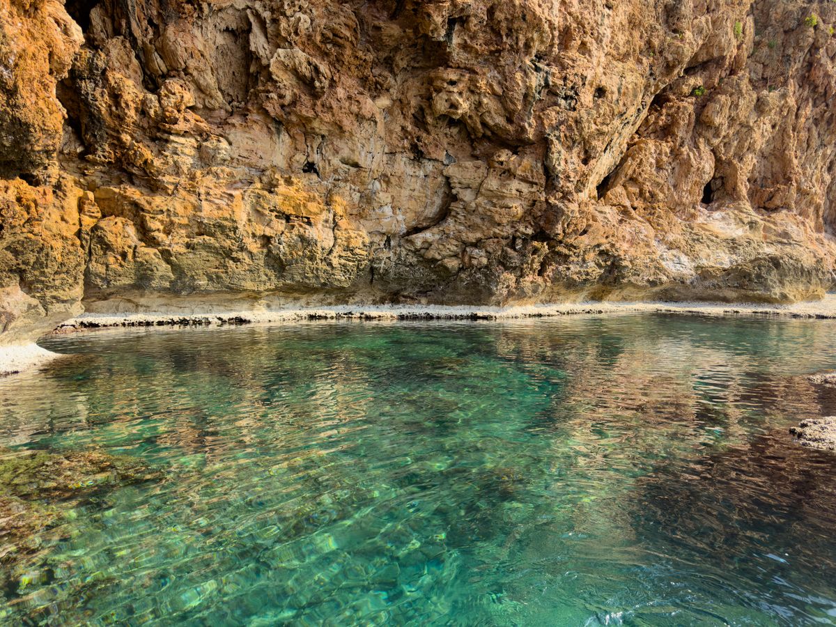 Kristallklares türkisfarbenes Wasser an einer schroffen Felswand
