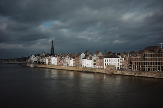 Picturesque view of Maastricht's riverside buildings under dramatic skies.