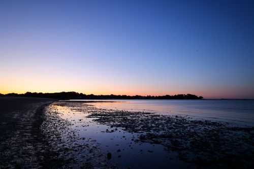 Free Peaceful coastal view with silhouette of trees at sunset, perfect for relaxation themes. Stock Photo