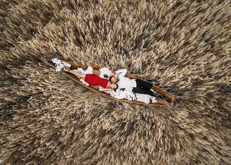 Couple Lying In Boat On Wheat Field