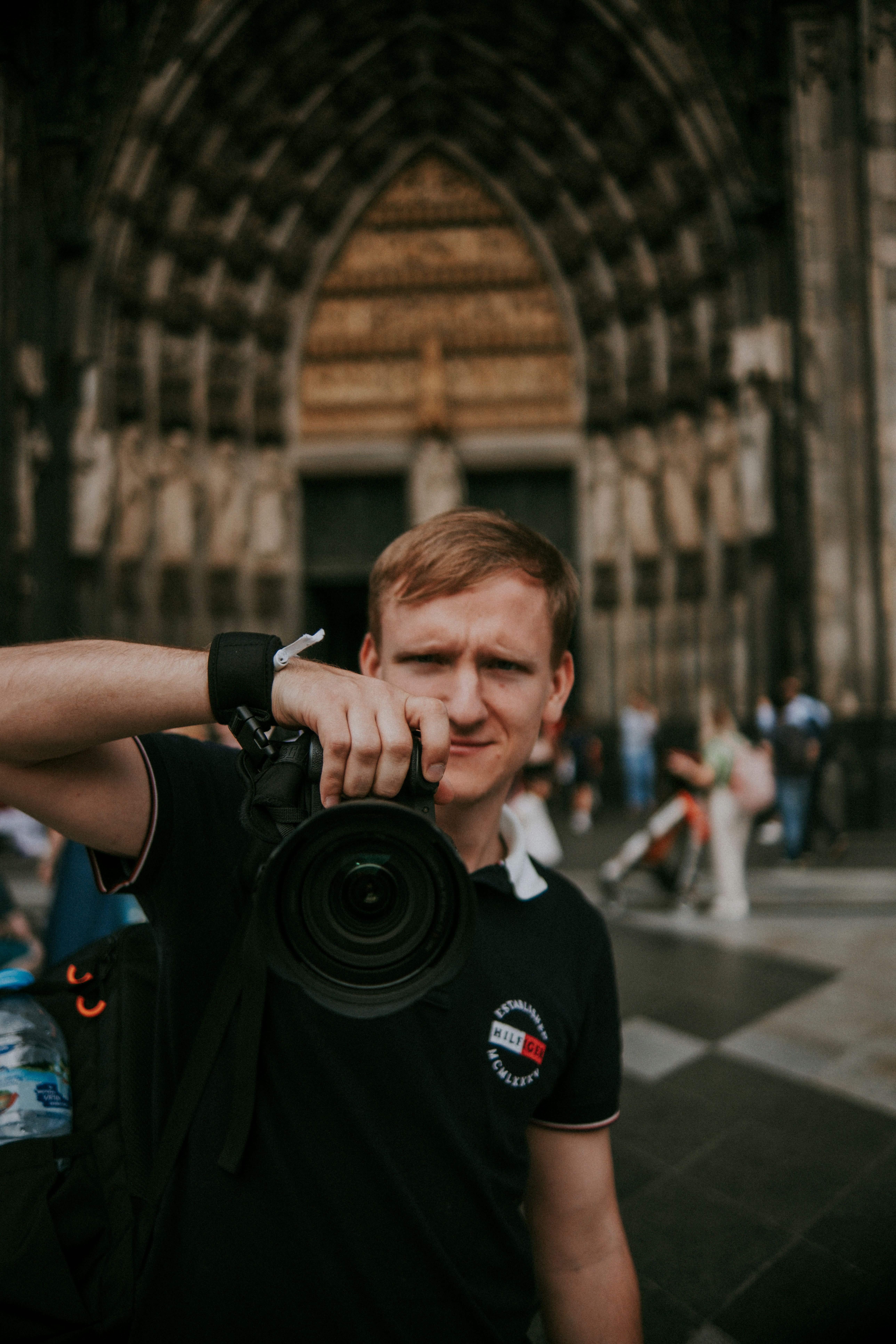 A photographer captures the moment outside a gothic cathedral entrance on a sunny day.
