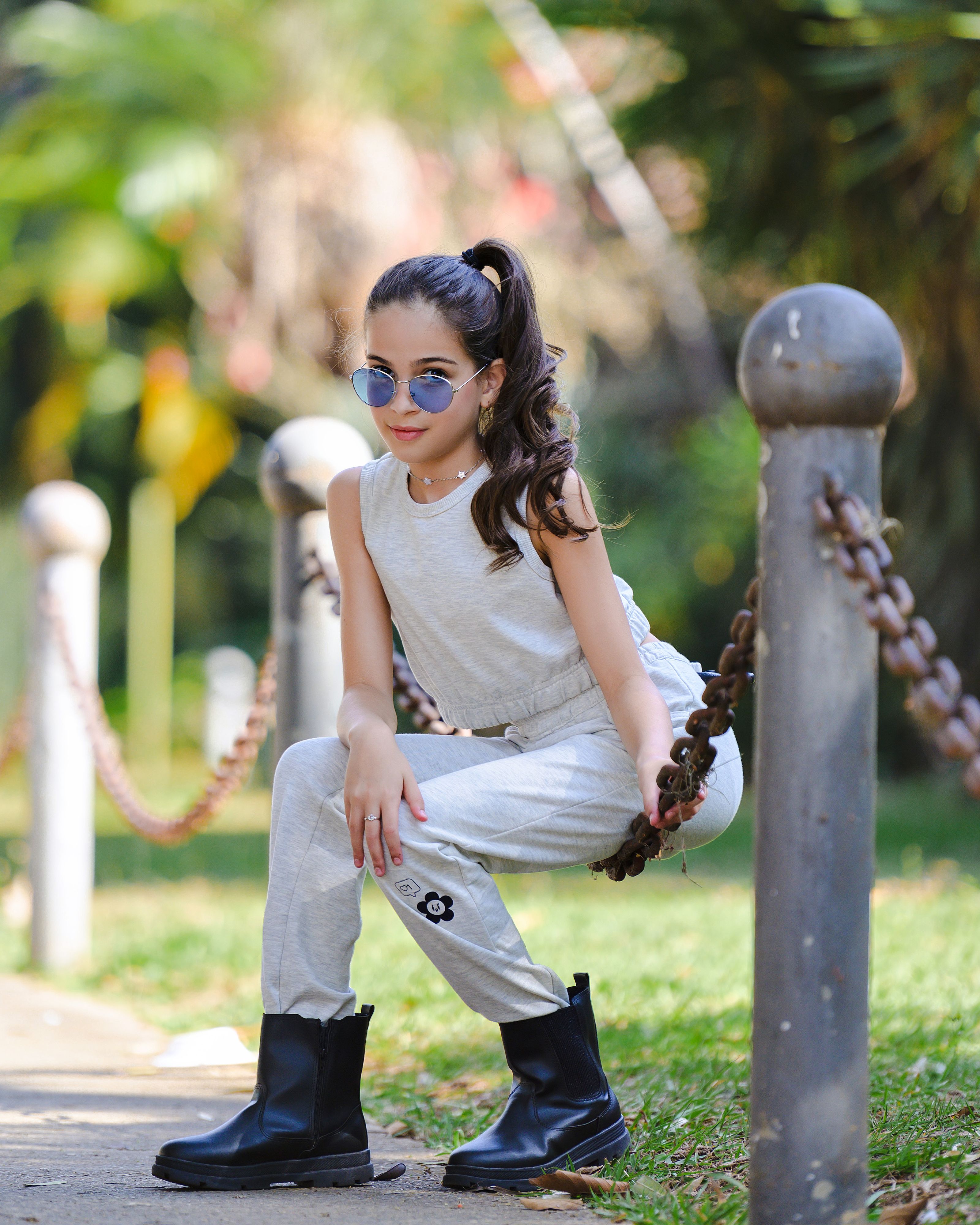 Adolescente elegante posando ao ar livre com roupas da moda e óculos de sol.