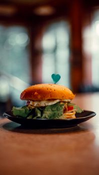 Appetizing gourmet burger on a plate with a heart-shaped pick, perfect for dining settings.