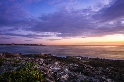 Free Dramatic sunset over Akumal's rocky coastline with vivid skies and tranquil oceanscape. Stock Photo
