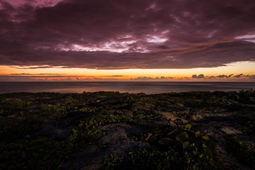 Breathtaking sunset over Akumal's rocky coast with dramatic skies and vibrant colors.
