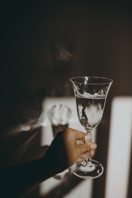 A person holding a glass of water in front of a window · Free Stock Photo