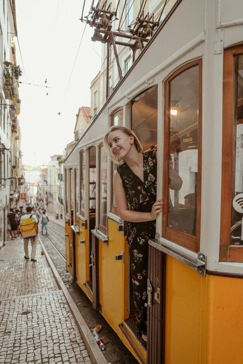 Smiling Woman Standing in the Doorway of a Yellow Tram on the Streets of Lisbon, Portugal 