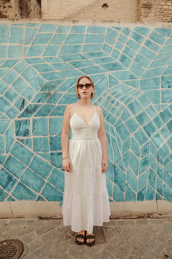 Model in a white strappy dress against a tiled wall, photo by Alina Rossoshanska on Pexels