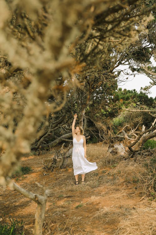 Woman in a White Dress Standing between Trees