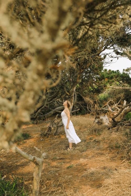 Free A woman in a white dress stands peacefully in a forest landscape, embracing nature's tranquility. Stock Photo