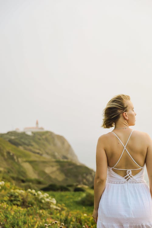 Woman in a White Dress Standing on the Background of the Cabo da Roca Lighthouse on the Coast of the Atlantic Ocean in Portugal