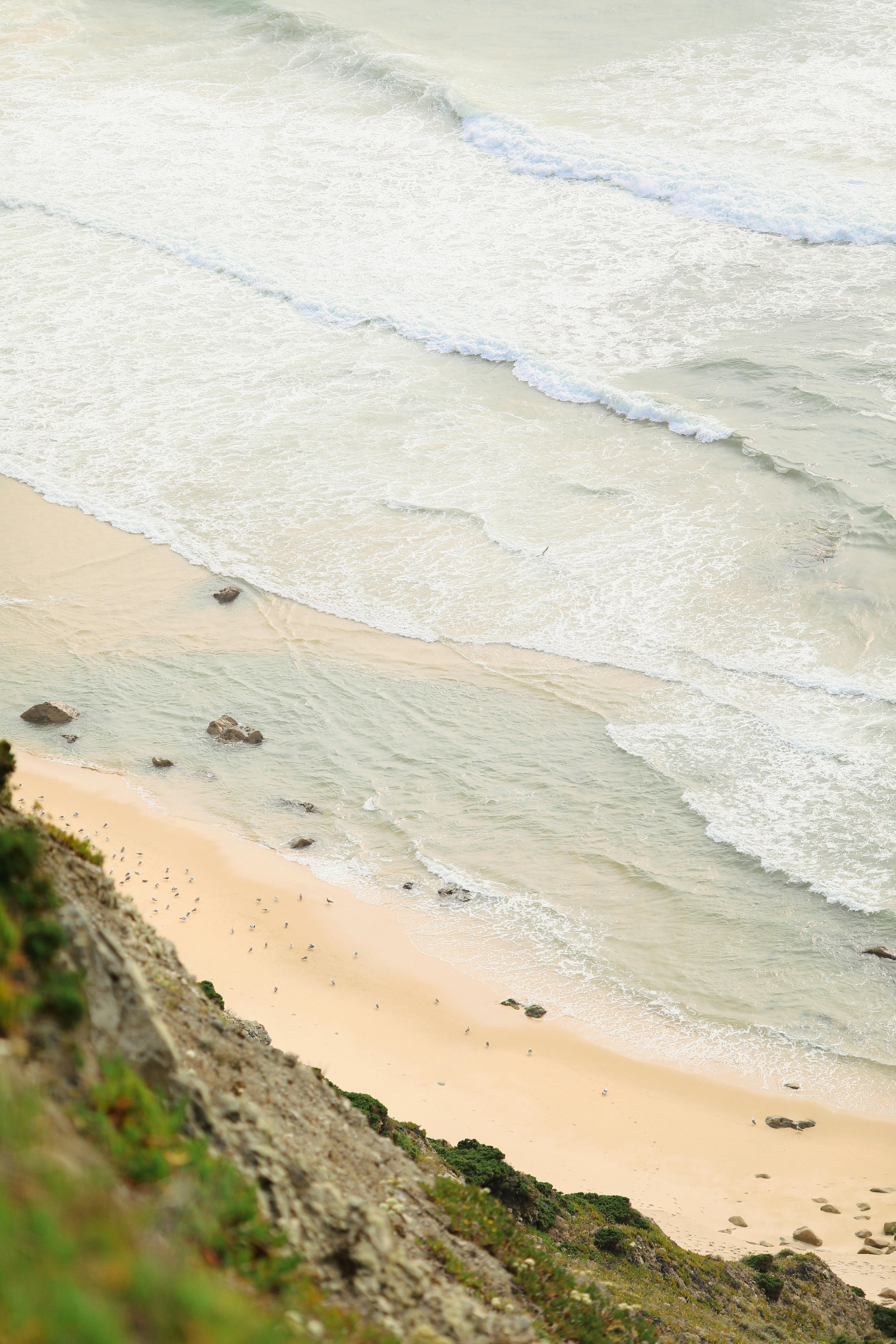 High angle view of a calm sandy beach with gentle waves rolling in from the ocean.