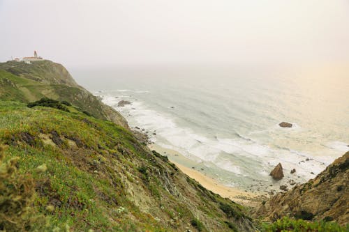 Green Cliffs on Sand Shore near Ocean