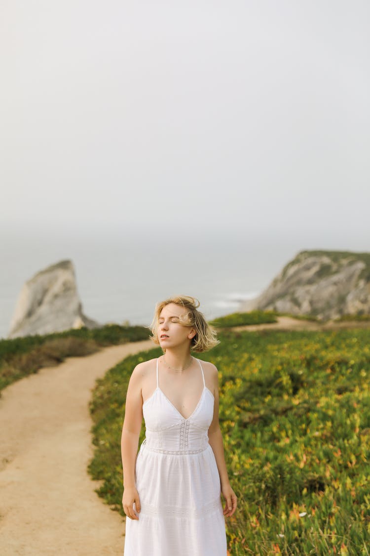 Woman Walking On Path On Rocky Seashore