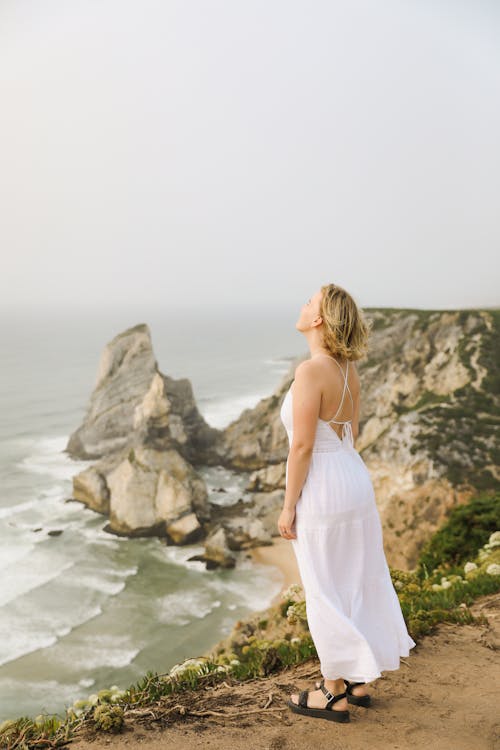 Woman Standing on Cliff on Seashore