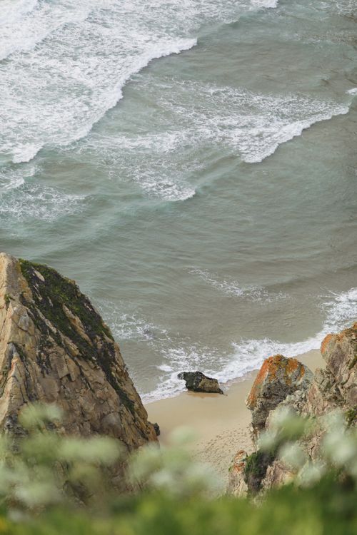 Free High-angle view of the waves crashing onto a rocky shoreline, with cliffs at Ursa Beach, Portugal. Stock Photo