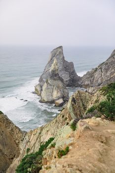 Breathtaking view of rugged cliffs and sea stacks along a coastline, with waves crashing below.