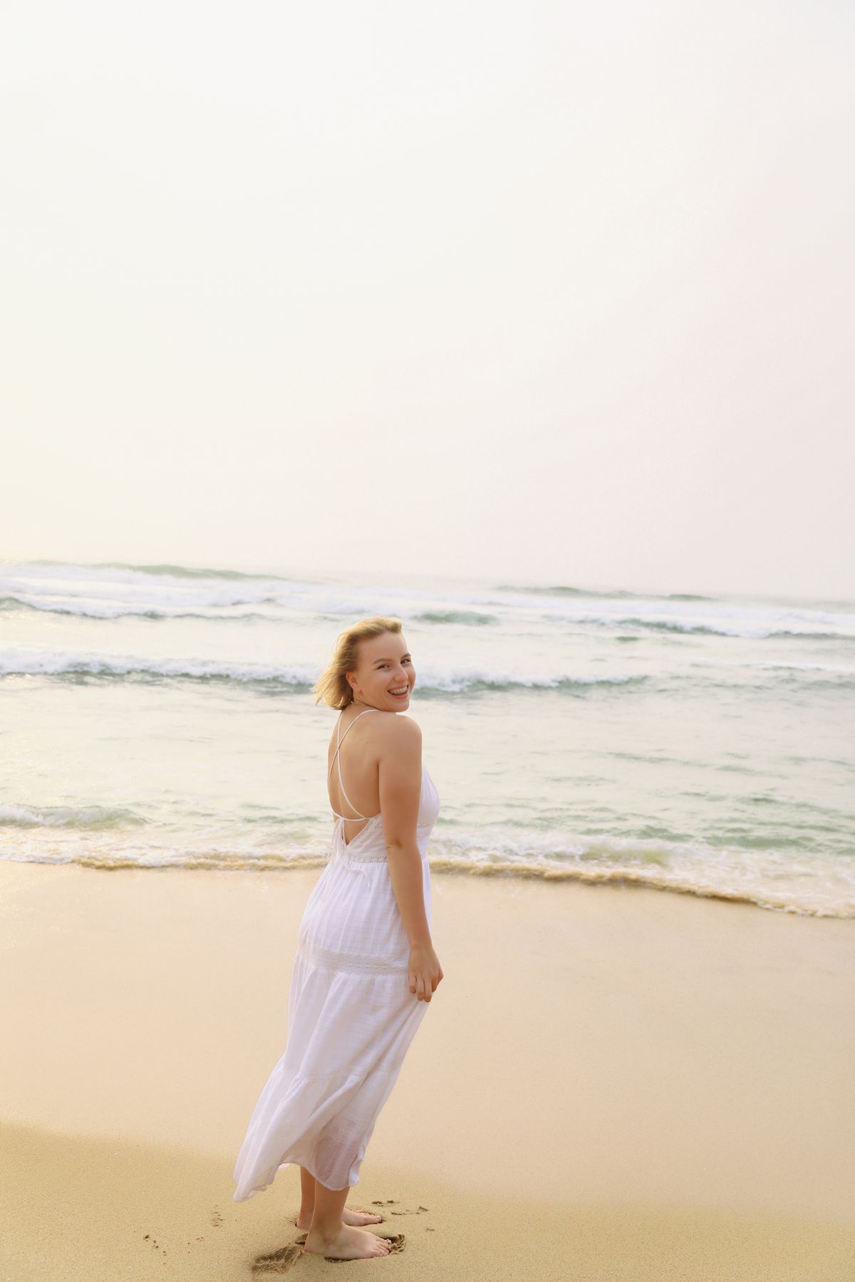 Woman in White Dress Sitting on Beach Rocks · Free Stock Photo