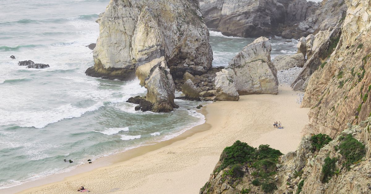 A beach with rocks and sand near the ocean · Free Stock Photo