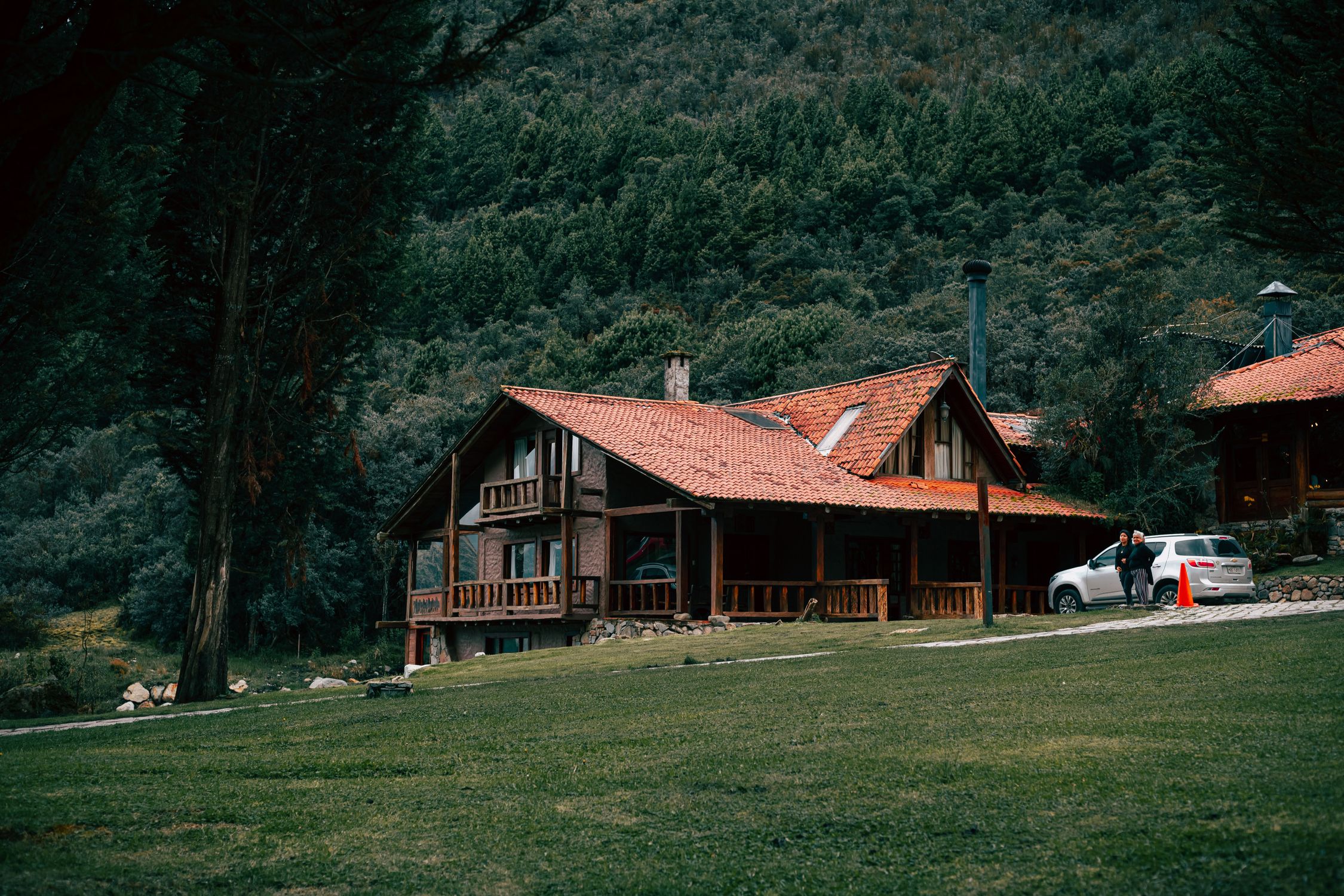 A picturesque wooden lodge surrounded by lush forest and mountains, perfect for a serene retreat.