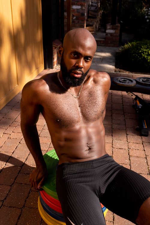 Free Young athletic man poses shirtless outside in sunlight, emphasizing fitness and strength. Stock Photo