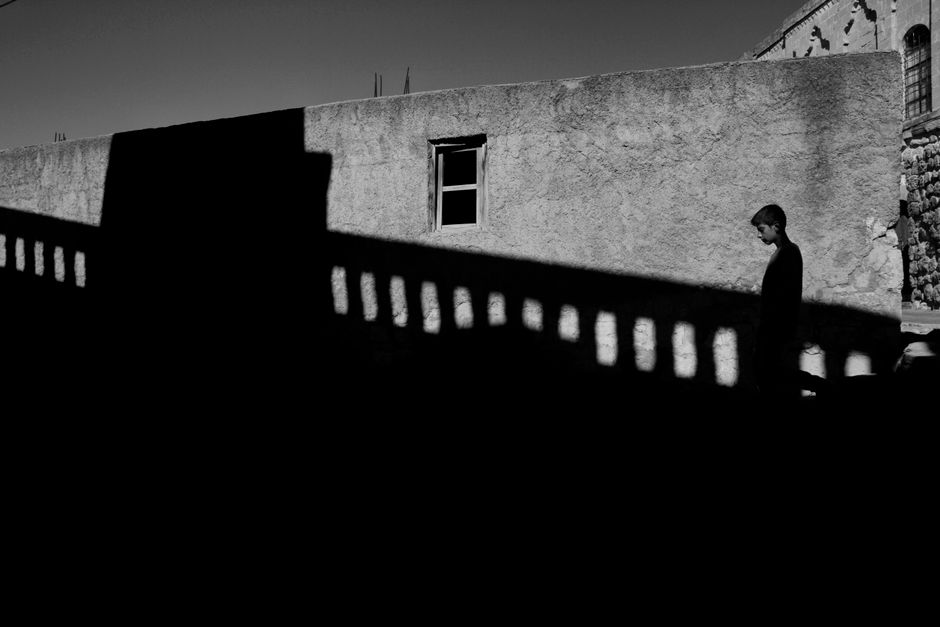 A striking black and white image of a boy walking by old buildings in Türkiye.
