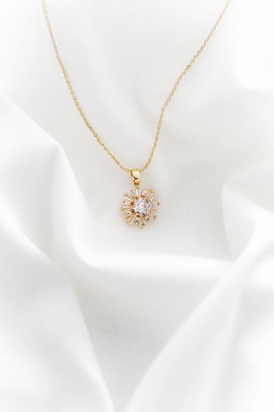 Fine gold chain with a pavé pendant on ivory silk. Photo by gül aksoy on Pexels