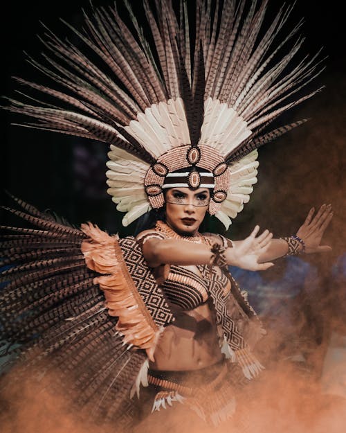 Woman in a Feather Costume and Headdress Posing at a Festival