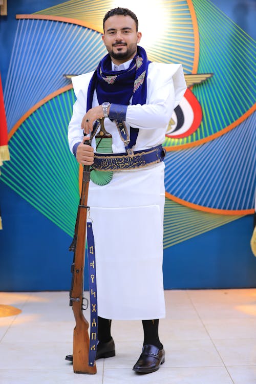 Young Man Wearing Traditional Clothing and Holding a Weapon 