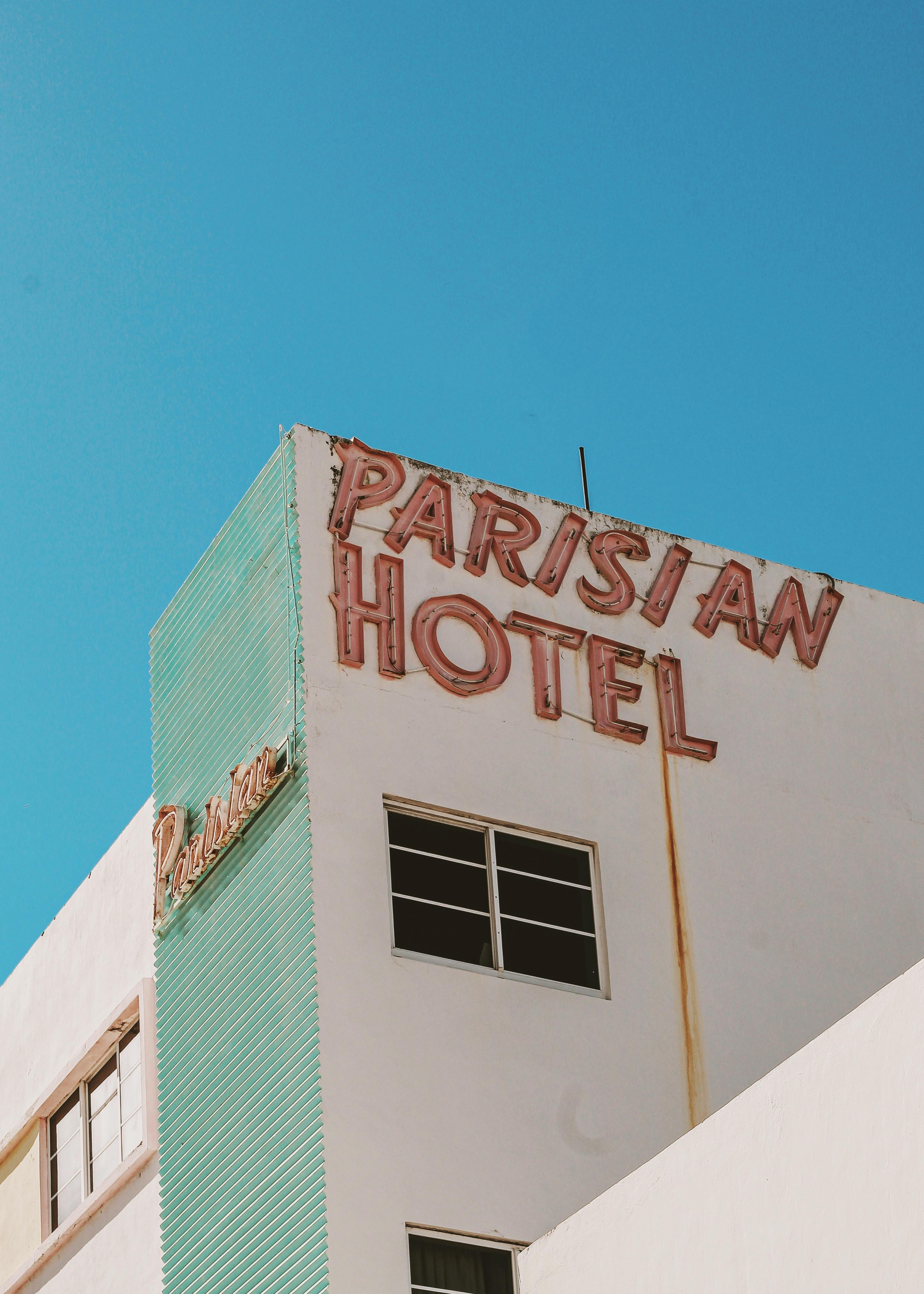 An exterior view of Parisian Hotel with vintage signage against a clear sky in Miami, FL.