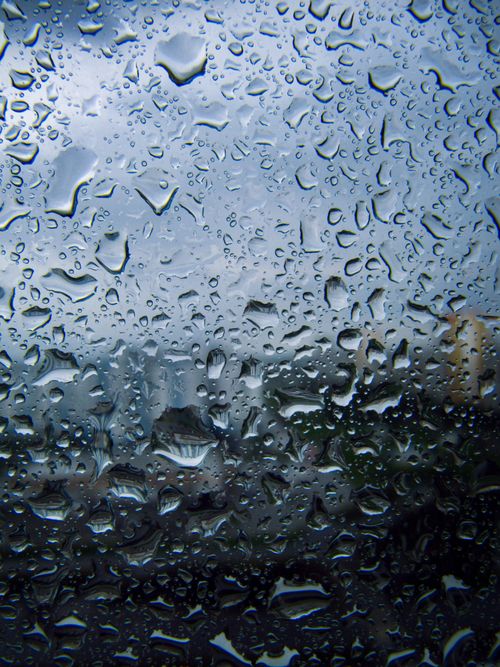 Free Raindrops on a window create an abstract pattern, blurring the cityscape view. Stock Photo