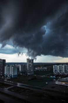 Aerial view of dark storm clouds looming over city buildings, creating a dramatic urban atmosphere.