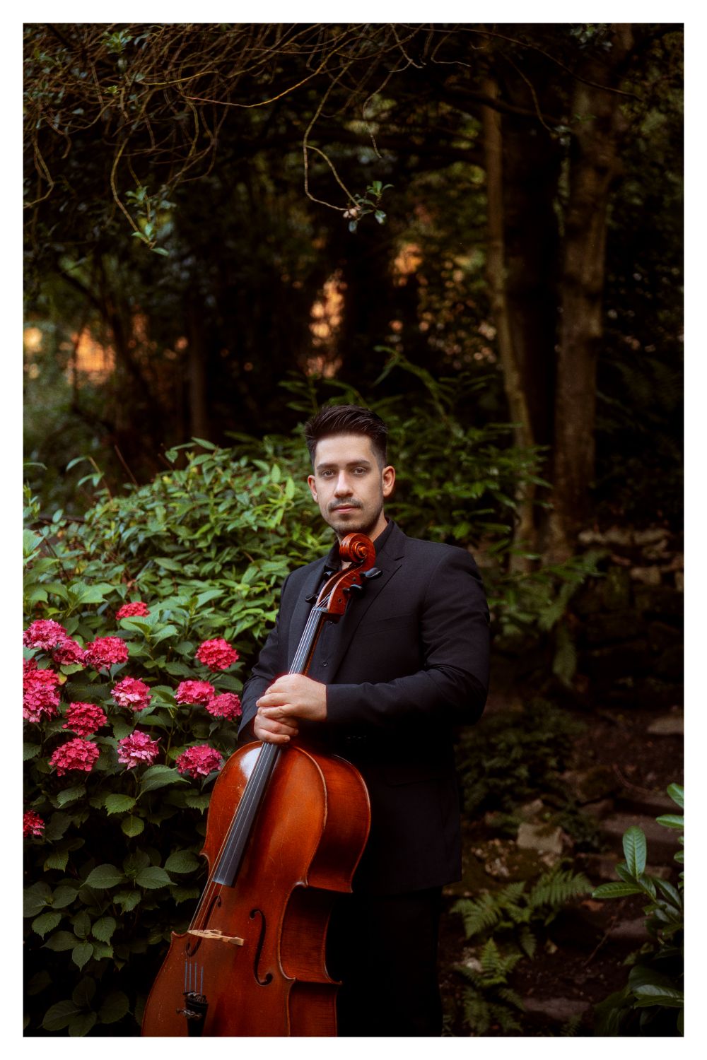 Cellist of Fermata Strings in a dark suit holding his cello