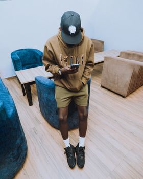 Man in casual attire using smartphone in modern indoor setting.