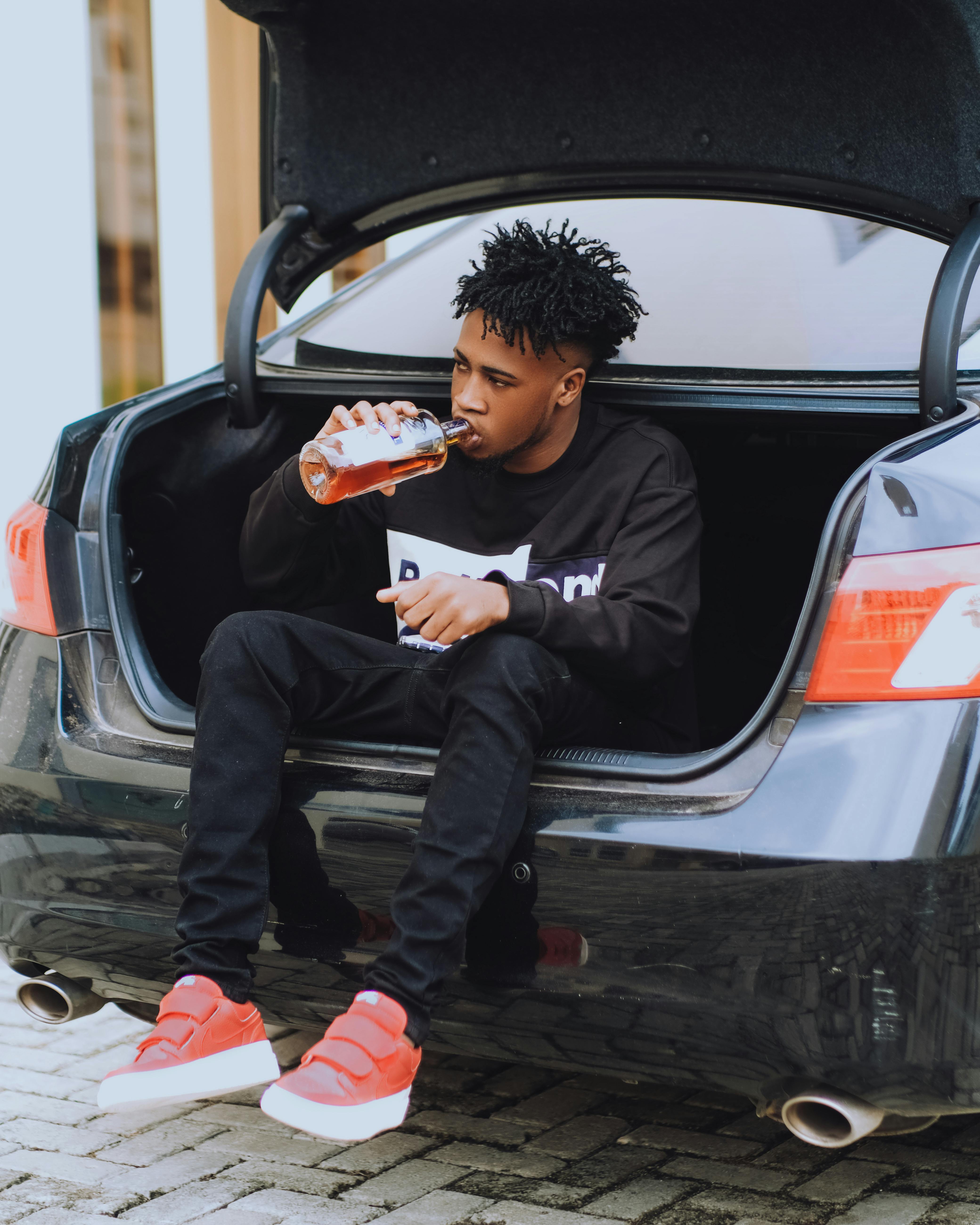 Man Drinking Alcohol and Sitting in Car Trunk · Free Stock Photo
