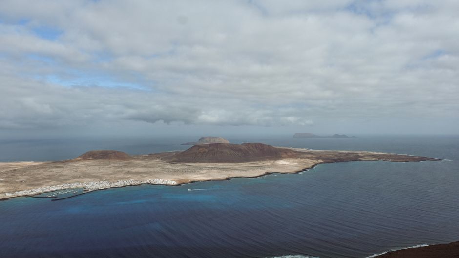 Breathtaking aerial view of La Graciosa Island with ocean and dramatic clouds, seen from Lanzarote.