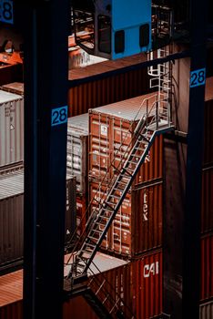 Elevated view of cargo containers with a metal staircase at a shipping facility.
