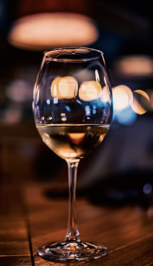 Free Close-up of wine glass with ambient lighting and lens flare, creating a warm and elegant atmosphere. Stock Photo