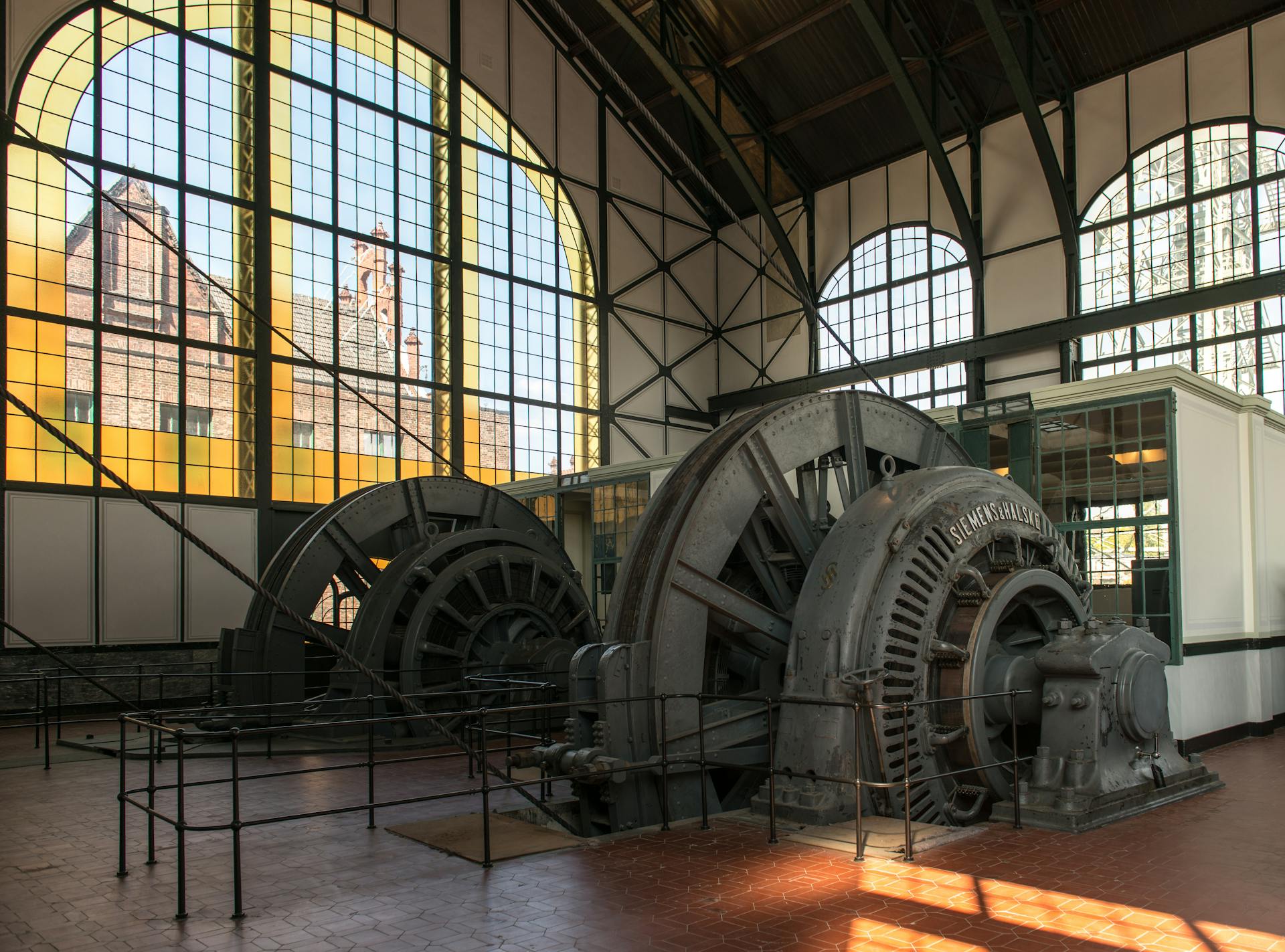 Interior view of the engine room in the Zollverein Coal Mine, showcasing historic machinery and large windows.