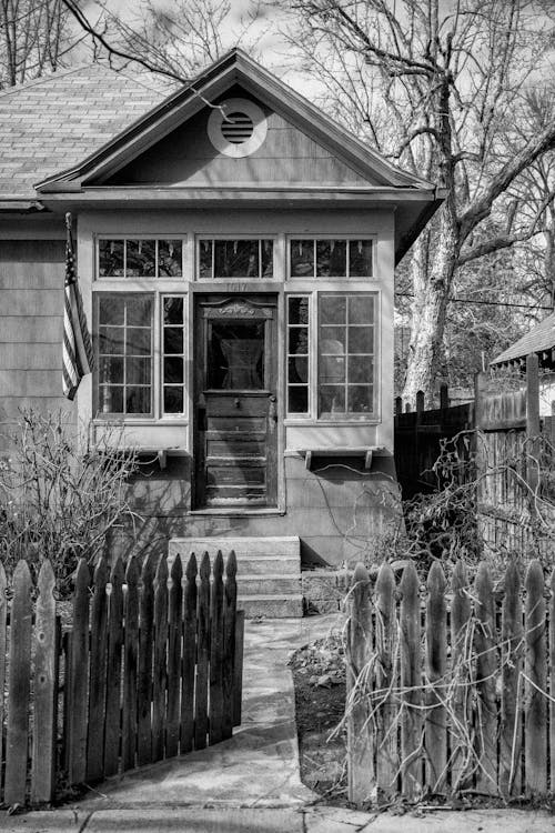 Black and White Picture of an Old House with a Fence 
