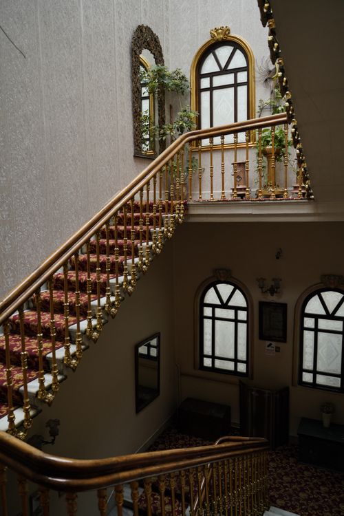 Free A grand vintage staircase with decorative railings and arched windows, evoking luxury and elegance. Stock Photo