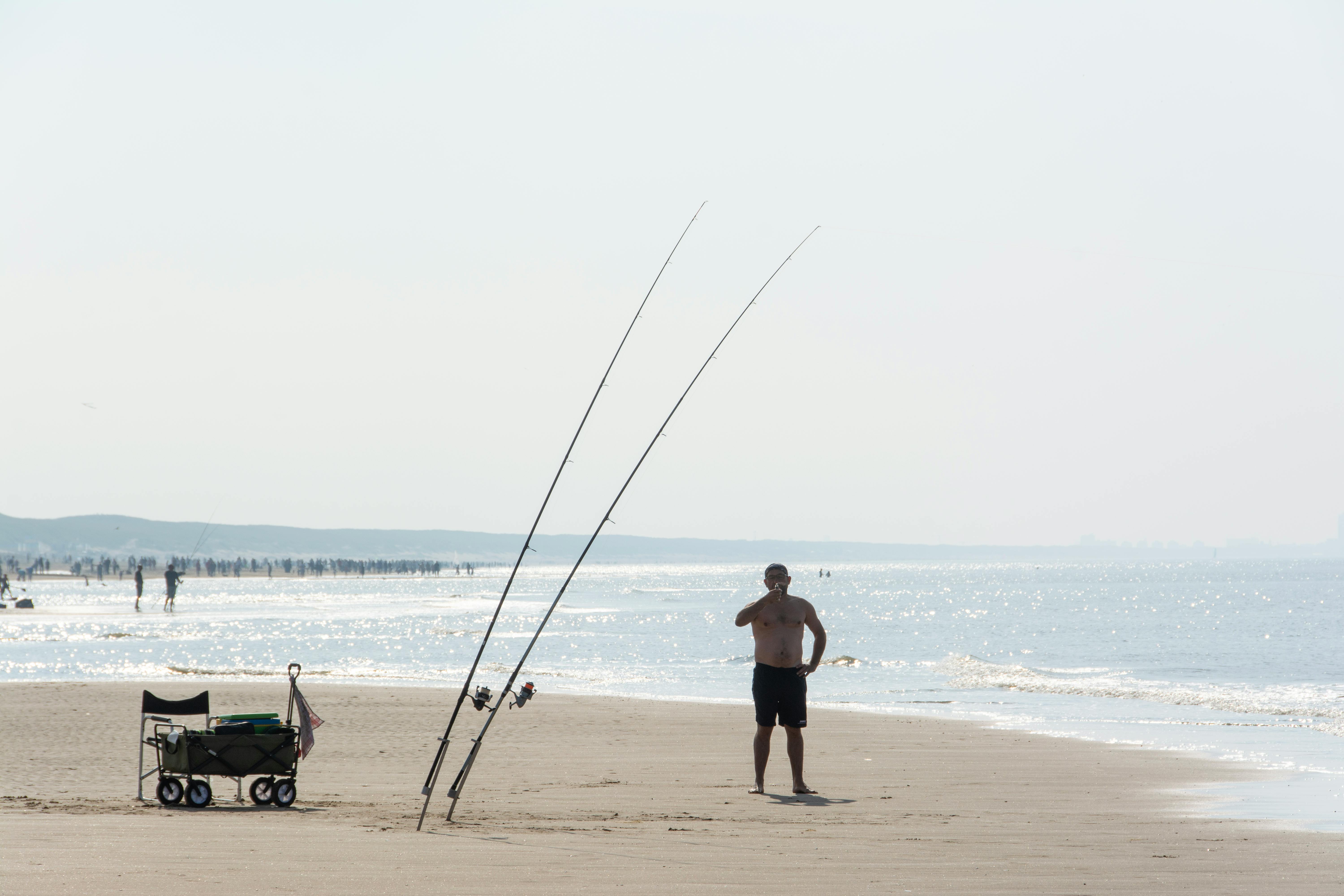 a man with fishing rods standing on the beach