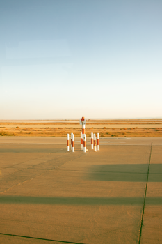 A quiet airport runway extending into a barren desert landscape under an overcast sky.
