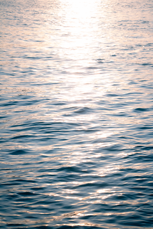 Free Sunlight reflecting on the rippling sea surface during sunset, creating a serene and peaceful ambiance. Stock Photo