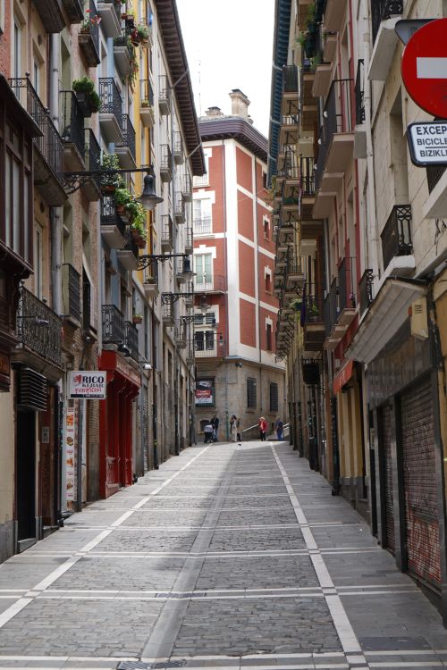 Free Narrow cobblestone street flanked by historic buildings in Pamplona, Spain. Ideal for travel and architecture themes. Stock Photo