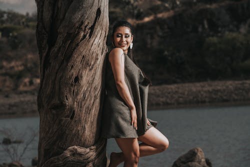 A Woman in a Mini Dress Posing by the Tree Trunk