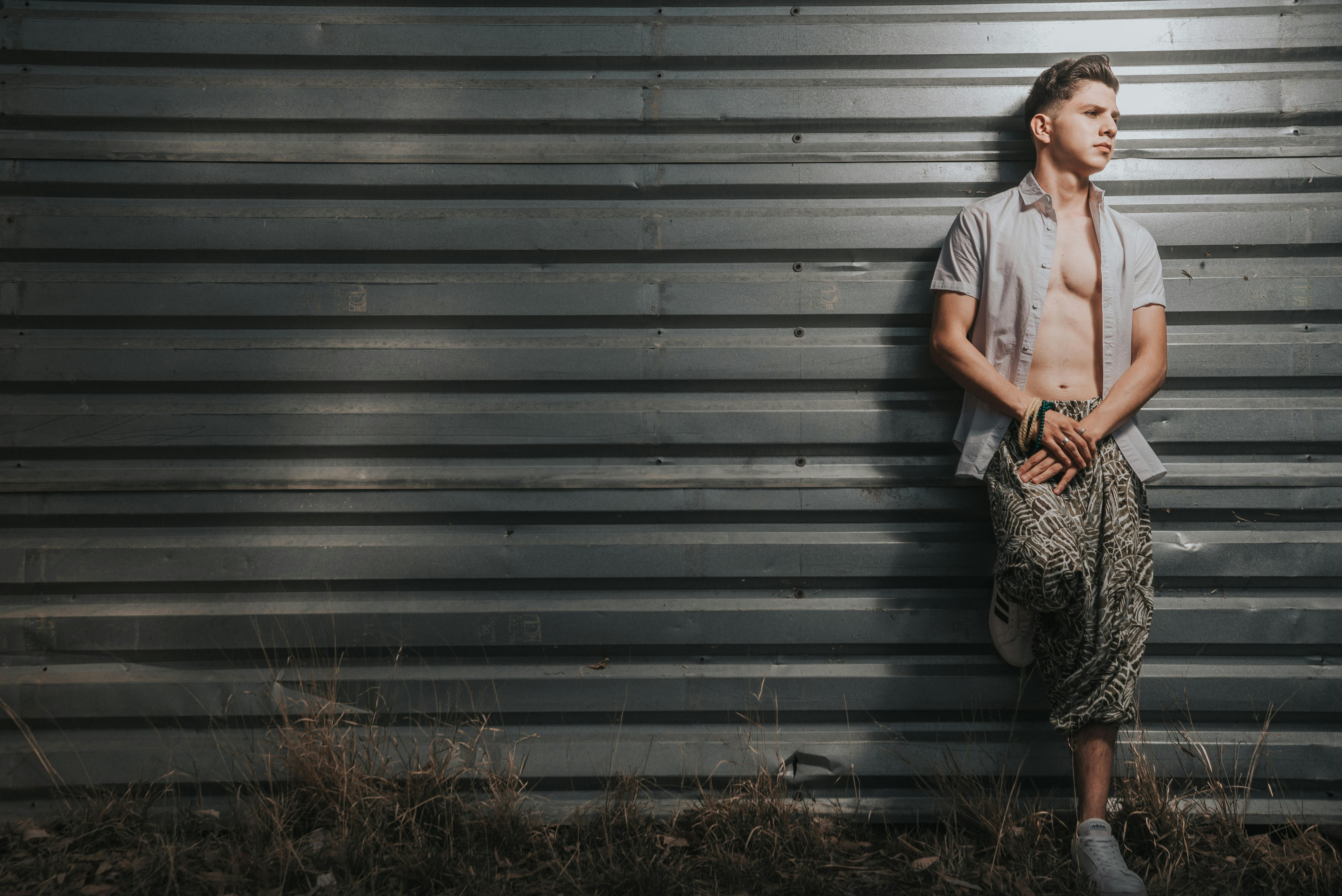 teenage boy in shirt leaning against metal wall