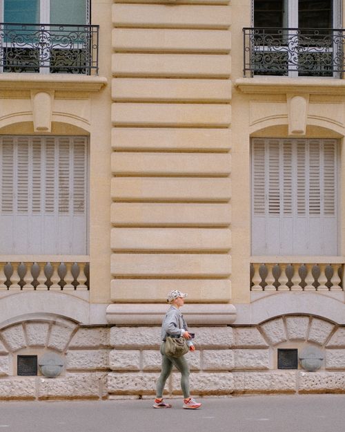 Free Woman walking along an urban street past elegant historic architecture. Stock Photo