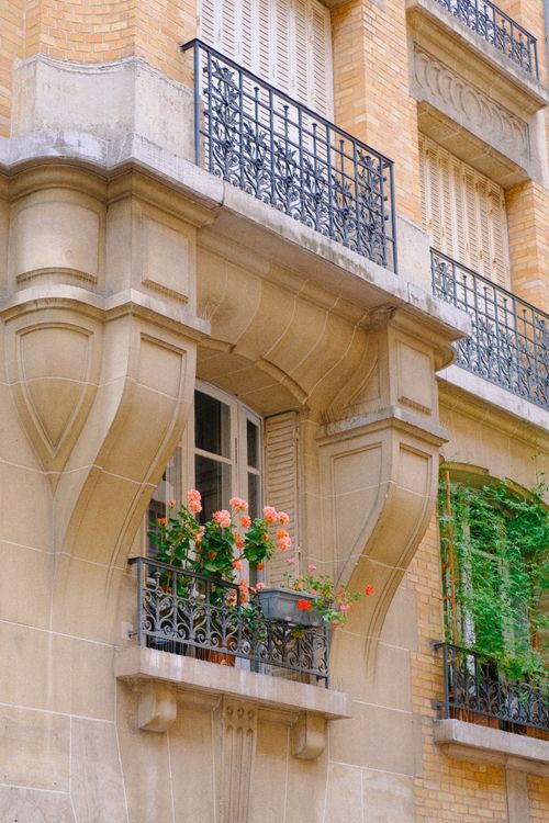 Free Charming city balcony adorned with vibrant red flowers and classic iron railings in an urban setting. Stock Photo