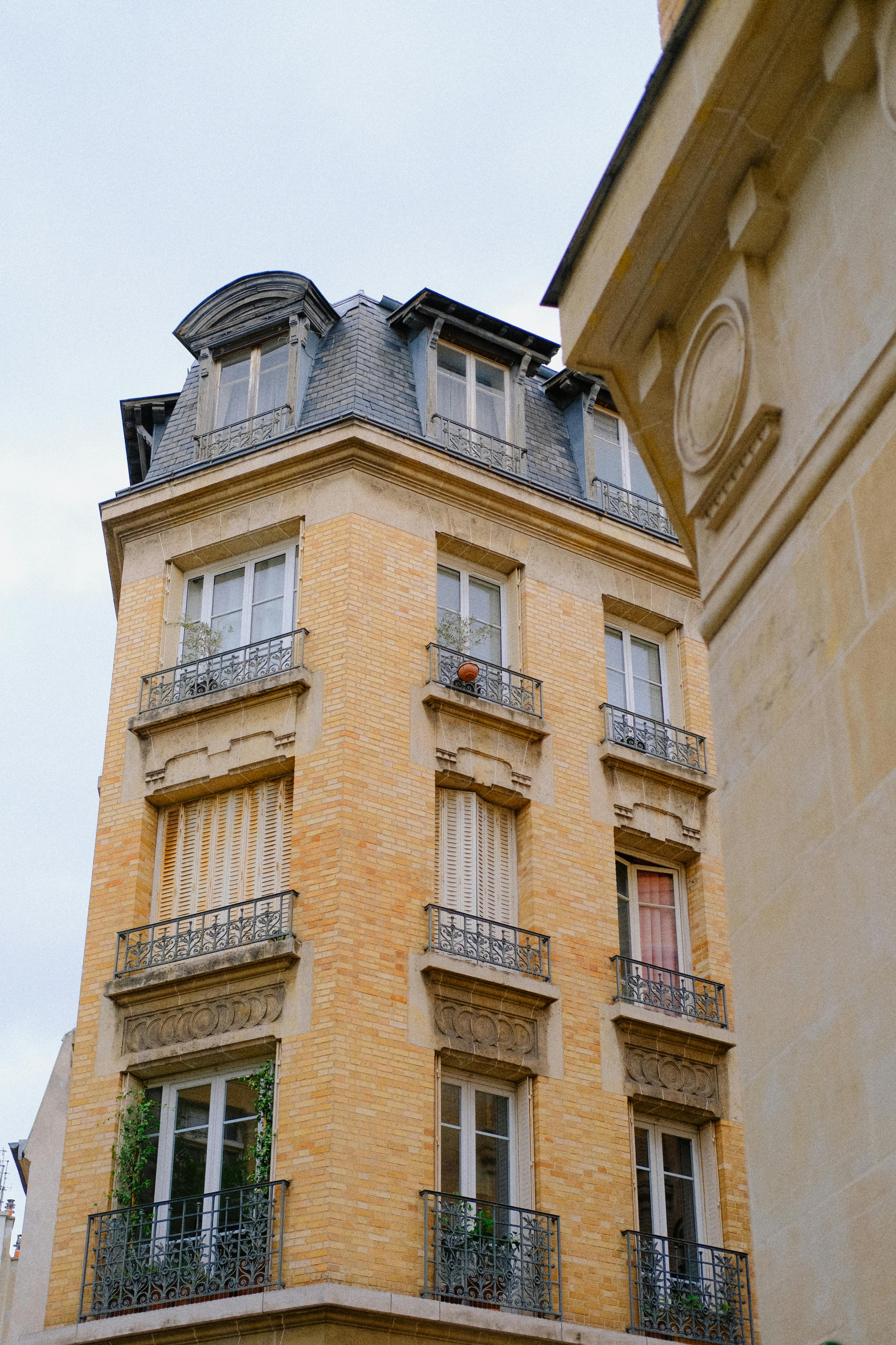 Charming city apartment building with decorative balconies and yellow brick facade.
